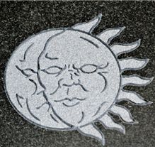 Detailed celestial sun and moon face etching on granite