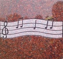 Musical notes and staff etching on red granite memorial